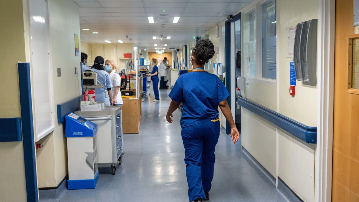 nurse walking down corridor in hospital - view from behind